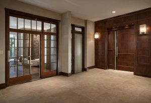 Luxury villa foyer with wide pivot-door circulation path and warm wood wall panels