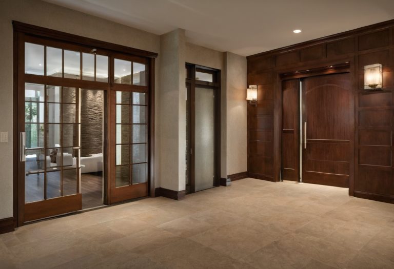 Luxury villa foyer with wide pivot-door circulation path and warm wood wall panels